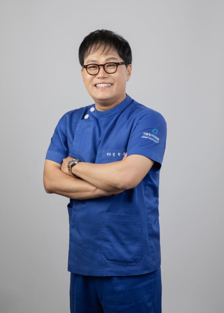 서울탑치과병원 임플란트 담당 원장 프로필 사진 (남색 진료복, 팔짱)