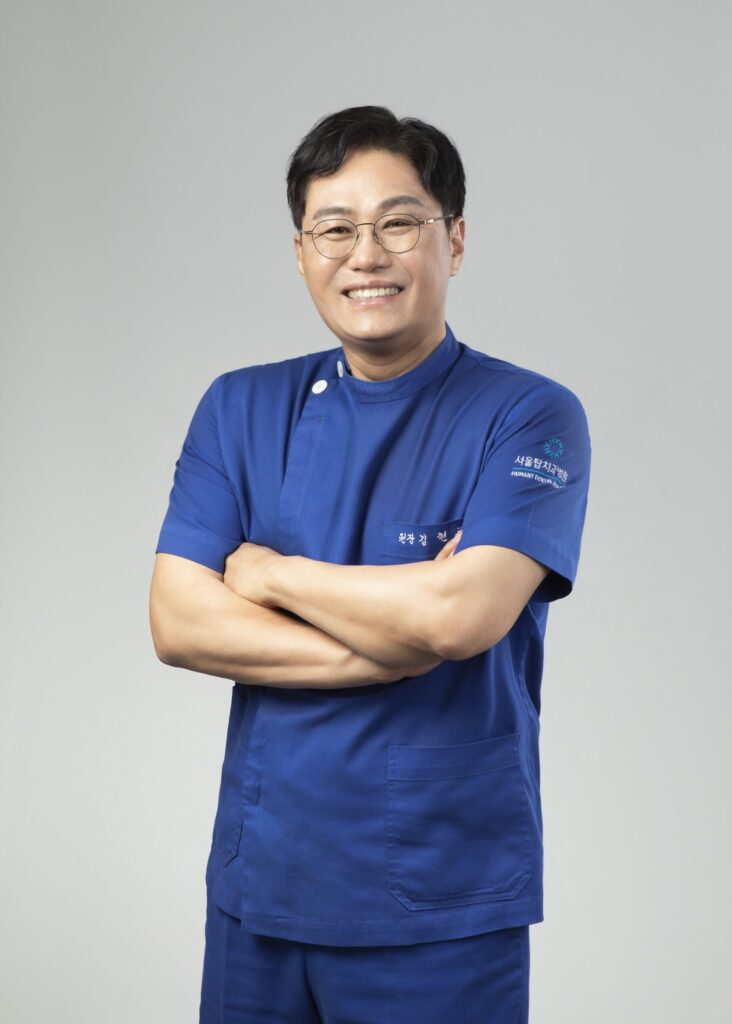 서울탑치과병원 임플란트 담당 원장 프로필 사진 (남색 진료복, 미소)