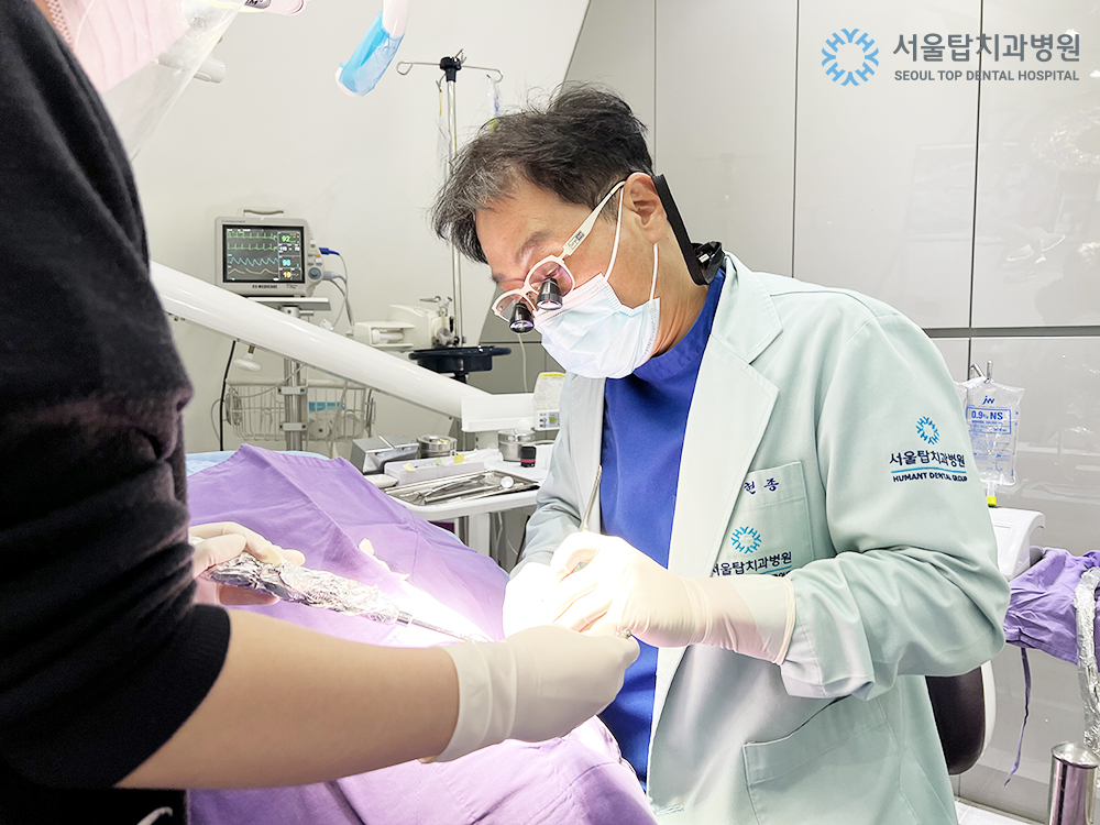서울탑치과병원 원장이 수술 가운을 입고 임플란트 수술을 집도하는 모습