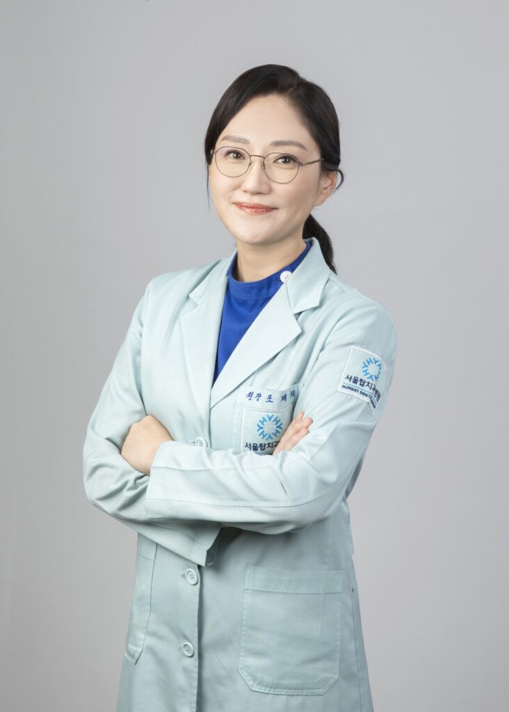 서울탑치과병원 교정센터 원장 프로필 사진 (민트색 가운, 팔짱)